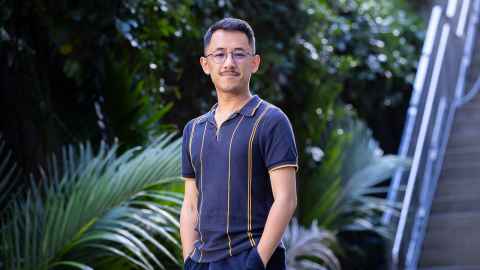 Doctoral researcher Tony Sriamporn in front of greenery.