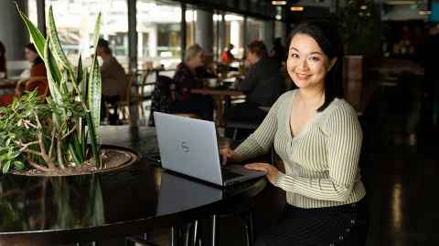 Professor Amy Chan using a laptop in a cafe.