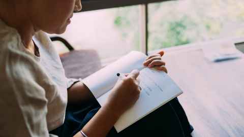 Person writing by hand in a notebook.