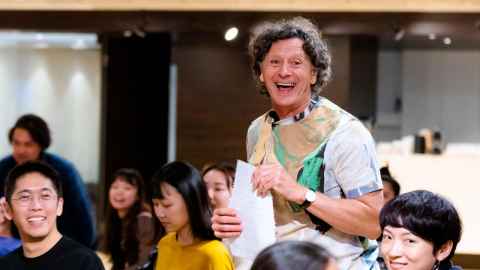 Professor Ralph Buck teaching in the Taipei National Theatre in Taiwan with students surrounding him.