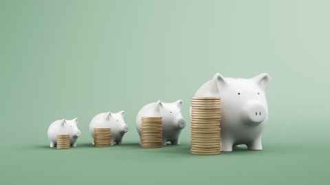 Piles of coins getting higher and higher, beside piggybanks