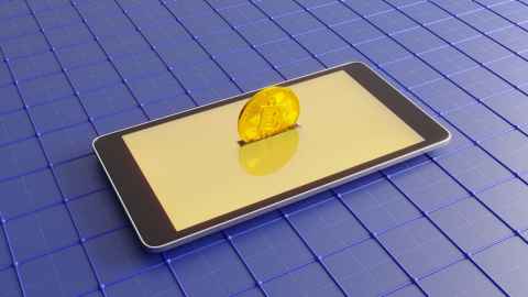 Conceptual image of mobile phone, with gold coin inserted into it. 