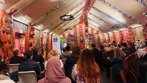 An audience sitting inside Waipapa Marae at the University of Auckland, attending a refugee event.