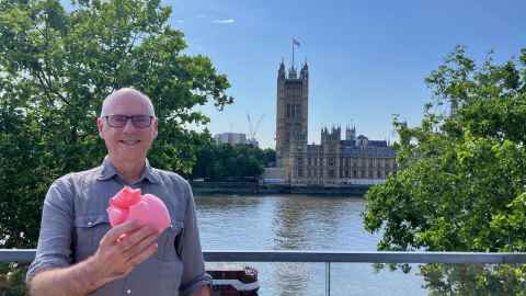 Alistair and a pink heart model with the Thames and the Houses of Parliament in the background