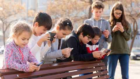 Row of seven kids all on their mobiles
