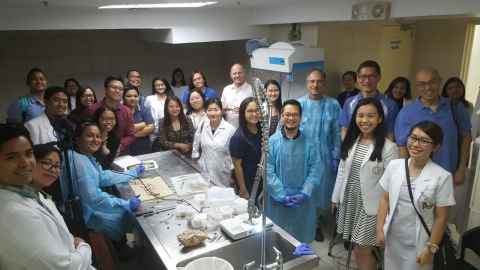 Dr Malvindar Singh-Bains (at table) teaching people in the Philippines.