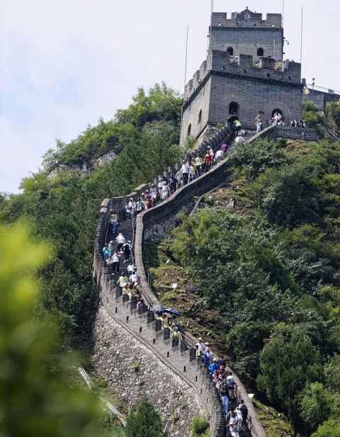 A group of people snake up a section of the Great Wall to a tower at the top.