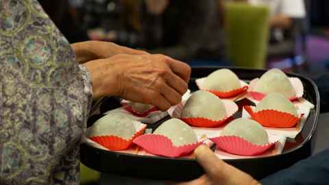 Ichigo daifuku, rice dumplings prepared with red bean paste and strawberries being handed out on a tray.