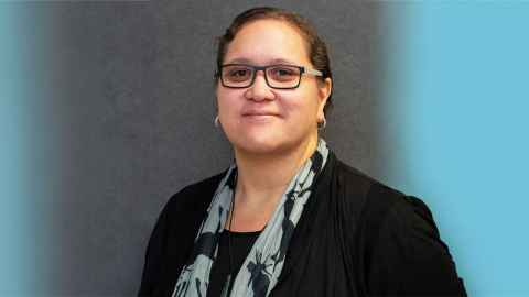 Head and shoulders of Associate Professor Krushil Watene wearing a black jacket and blue and black scarf.