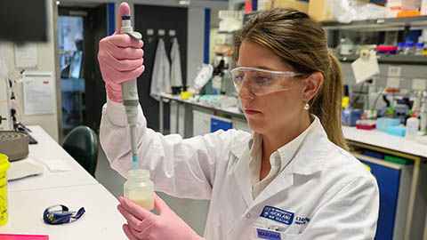 Mariana in the lab with a bottle of breastmilk and a syringe