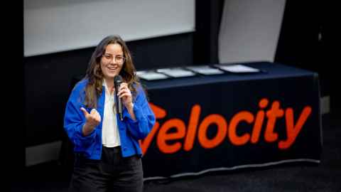 Andreia on stage in front of 'Velocity' sign