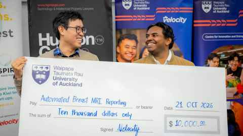They stand behind an oversized cheque, grinning