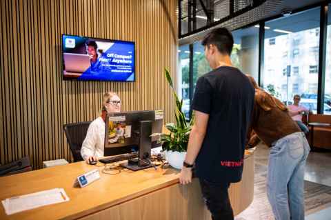View of the Waipārūrū reception desk with one person behind the desk speaking to two residents in front of the desk