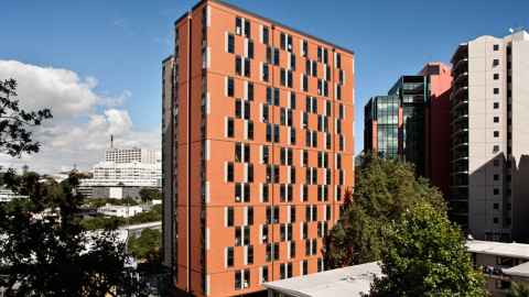 A tall orange building, with Auckland Hospital in the background.