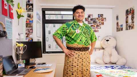 Lolo stands in his room with hands on his hips proudly wearing his ta'ovala.