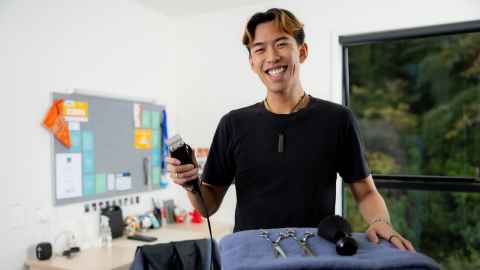 Jonathan stands in front of his hair cutting equipment and in his room