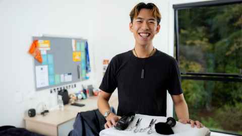 Jonathan stands in front of his hair cutting equipment and in his room