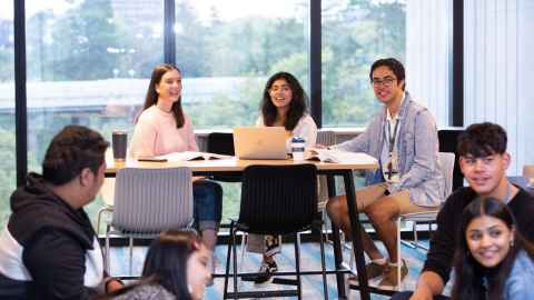 Three students in a common area sitting around a table chatting