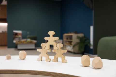 Three wooden blocks shaped like humans stacked on top of each other in the foreground.