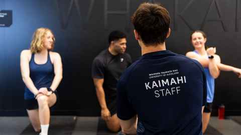 member lifting weights supported by a personal trainer