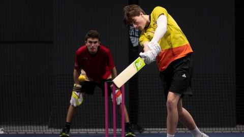 Students playing interfaculty indoor cricket