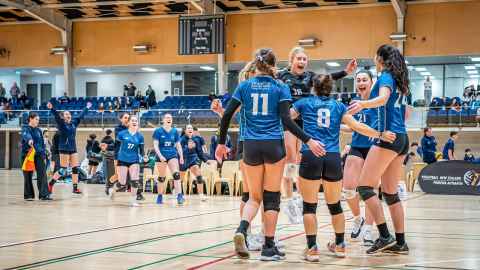 Photo of female volleyball team celebrating during nationals game