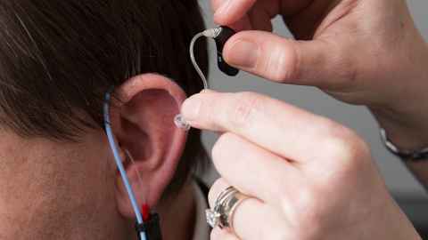 A hearing aid being fitted to an ear.