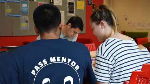 Image of three people studying. Two have their backs to the camera, one is a PASS Mentor
