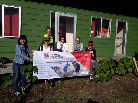 Group of six people holding a Volunteer Impact Week banner.