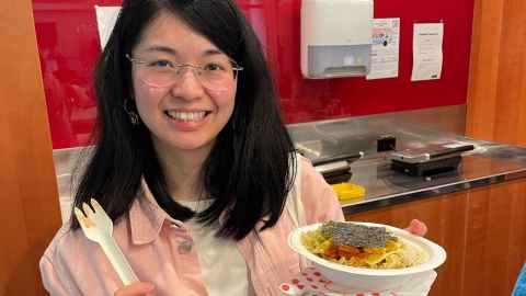 A student holding a ramen bowl