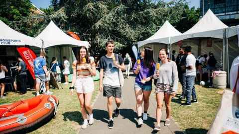 Four students walk through Clubs Expo on campus