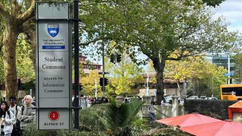 An intersection with trees, buildings and a sign saying 'Student commons, access to information commons'.