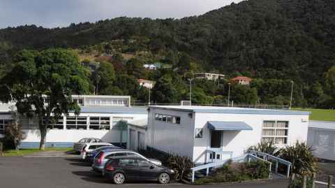 Buildings, a car park and trees dotted with houses in the background.