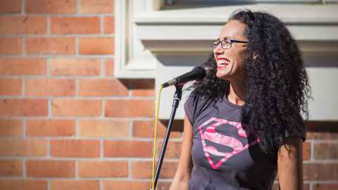 A woman with long, black, curly hair wearing a Superman t-shirt.