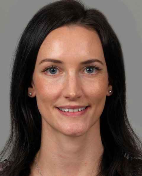 A dark-haired, blue-eyed woman, smiling.