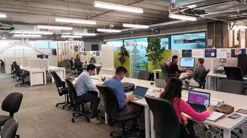 People working in a modern, open-plan office space.