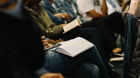 Students in a lecture with notebooks in their laps. 