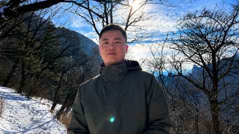A picture of Haokun Song in the winter with the sun shining behind him. 