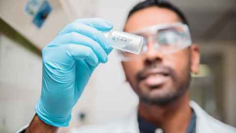 student inspecting vial of chemical powder in a lab