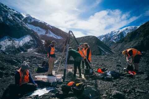 Students doing fieldwork surrounded by ice capped mountains