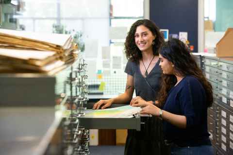 A photograph of Alana Jacobson-Pepere and a friend looking over maps