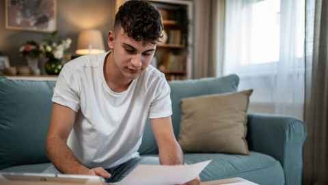 Student looking at document and working on laptop