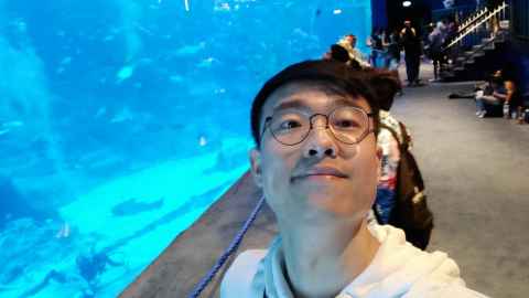 A photograph of Wenjie Wu against an aquarium background. 