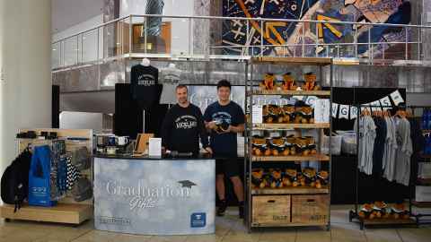 A stand with graduation bears, t-shirts, bags and other merchandise.