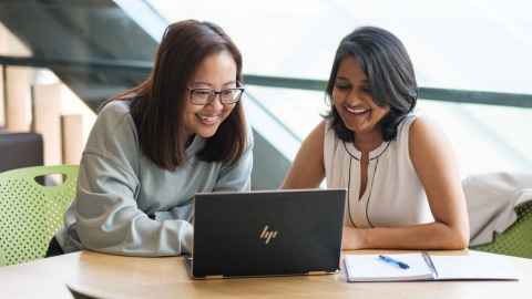 Two doctoral candidates looking at their laptop at the University of Auckland.