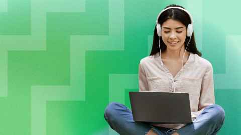Image of a student using a laptop with over ear headphones on and a green background. 