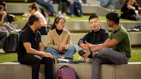 Four students sitting outside together, talking.