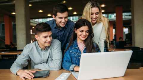 A group of people clustered around a laptop.