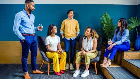 A group of people, some sitting, some standing, smiling at each other.
