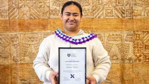 Rachel Mata holding a framed Tupu Pasifika Award certificate. 